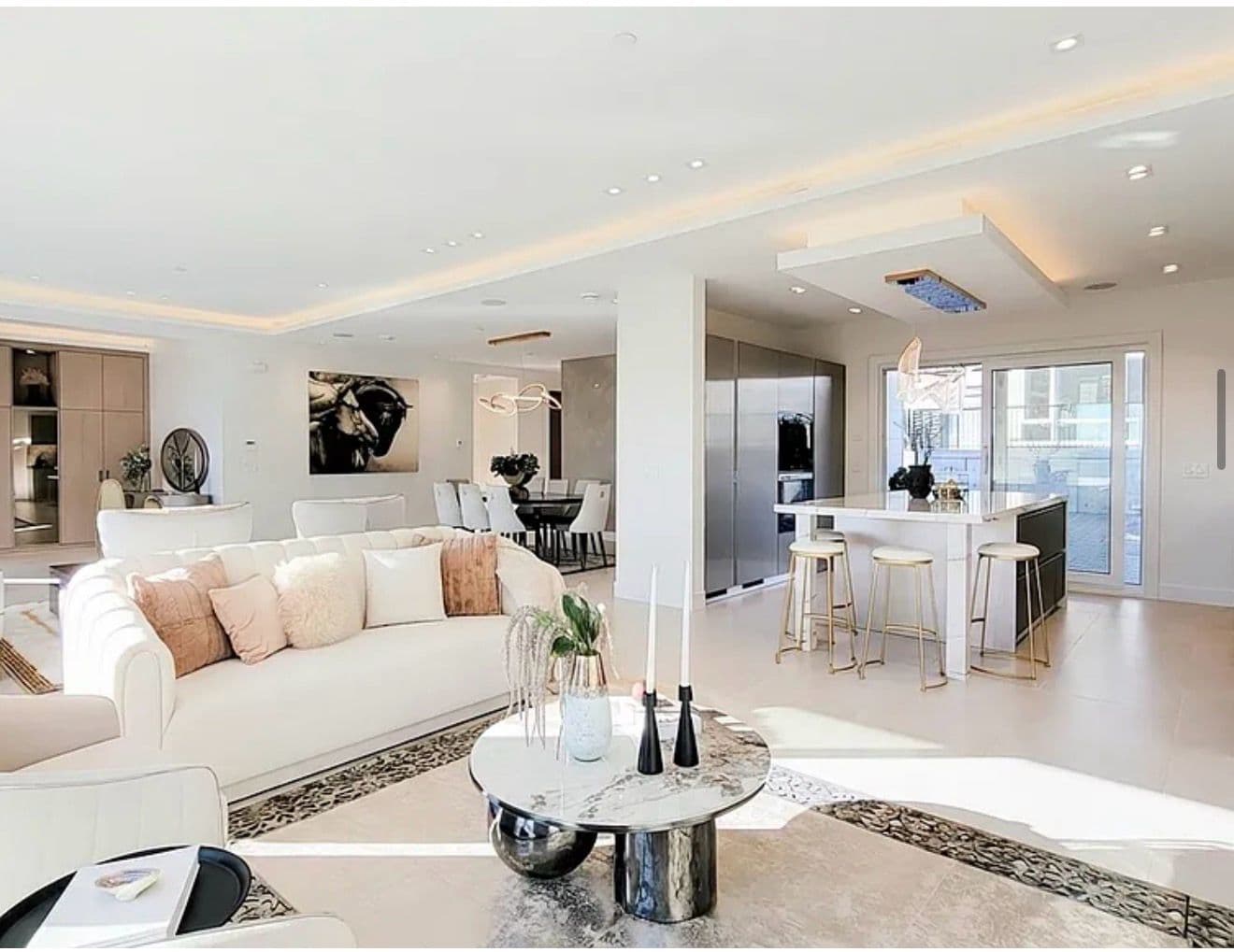 Bright open-plan staged living and kitchen with marble accents and warm styling