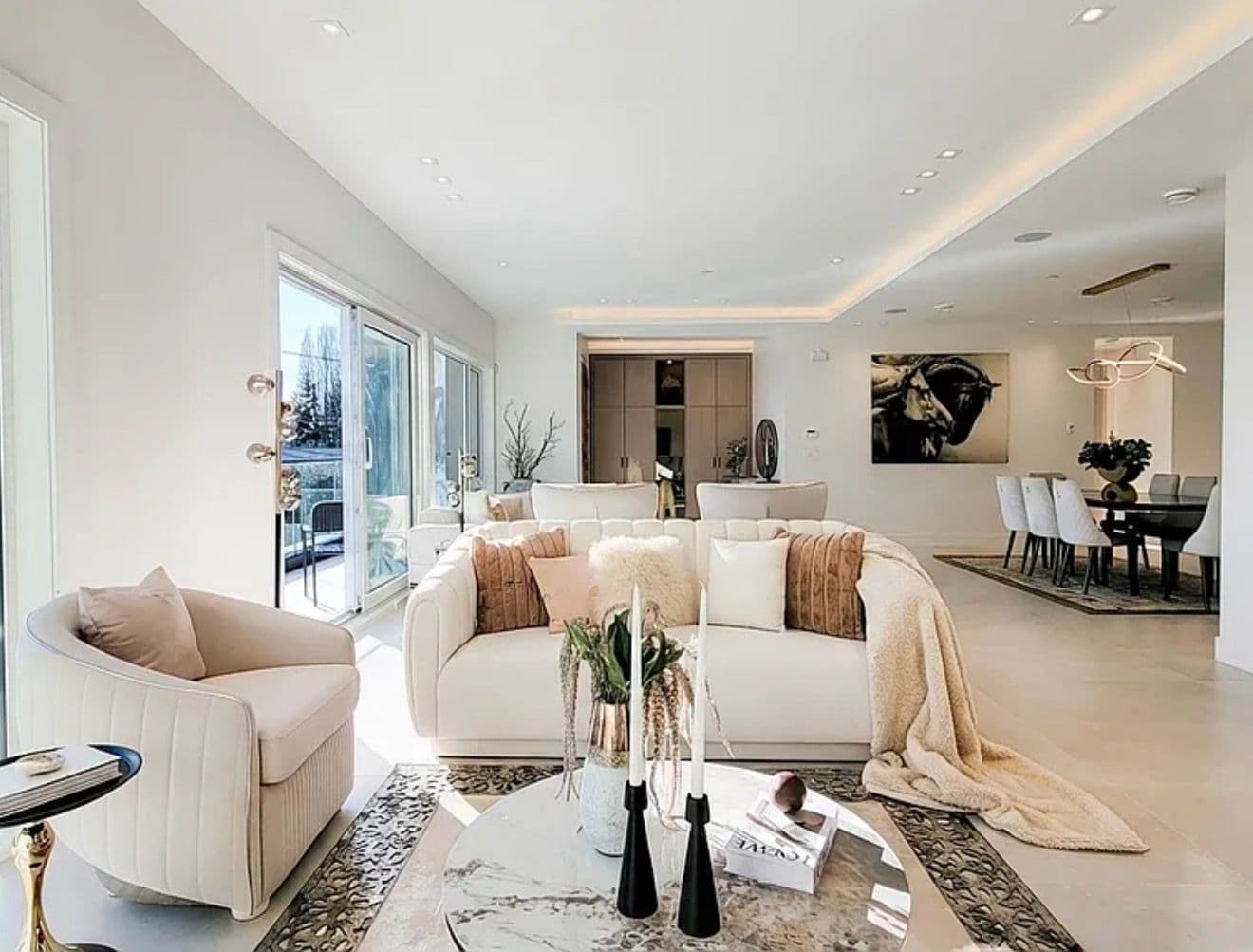 Open-plan staged living and dining space with cream sofas and soft blush styling